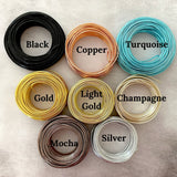Coils of wire on a cement looking flatlay. Colors: black, copper, turquoise, gold, light gold, champagne, mocha and silver.