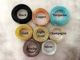 Coils of various colors of wire on a cement background. Color options are: Black, Copper, Champagne, Gold, Light Gold, Mocha, Silver and Turquoise