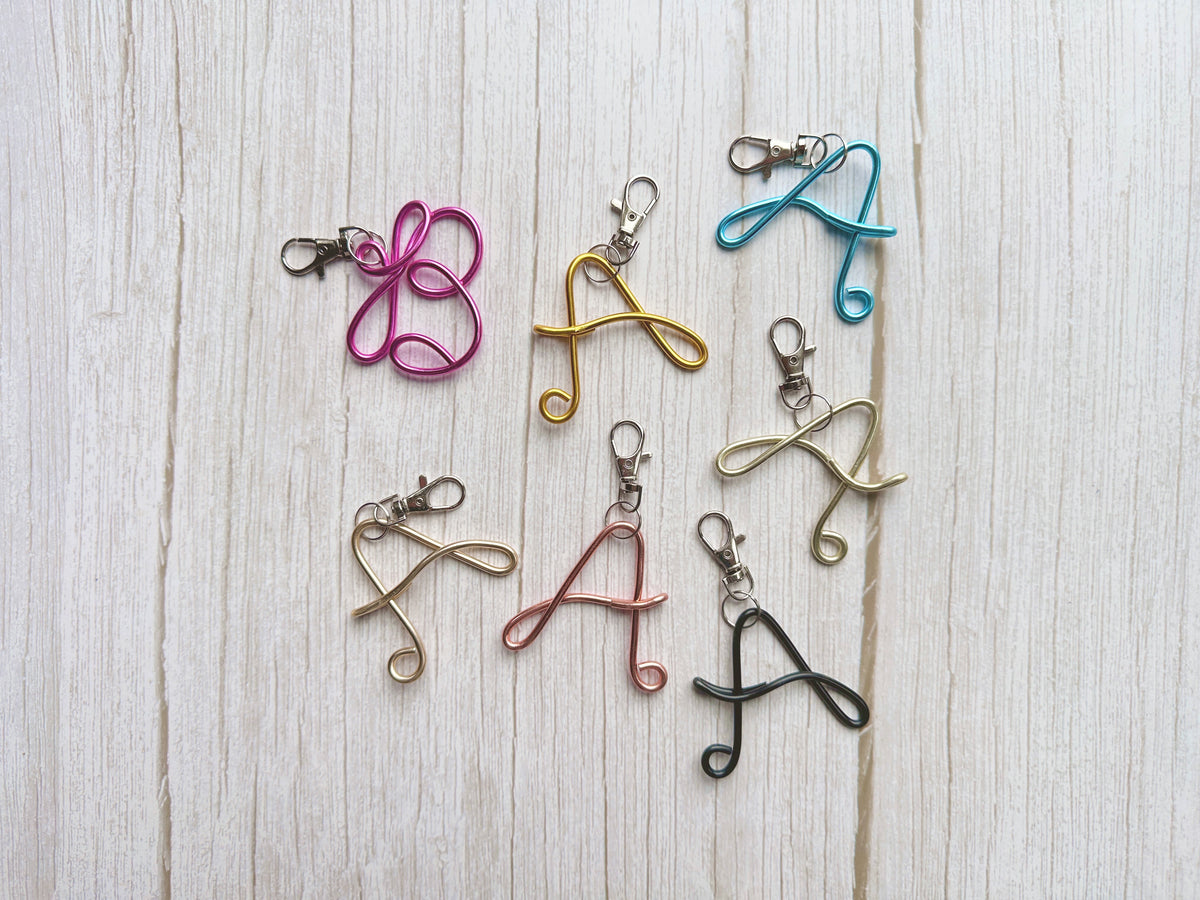 Personalized wire initial keychains and bag charms featuring handmade monogram letters in assorted colors.