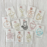 A collection of wire bookmarks or planner clips in a variety of colors attached to branded backing.