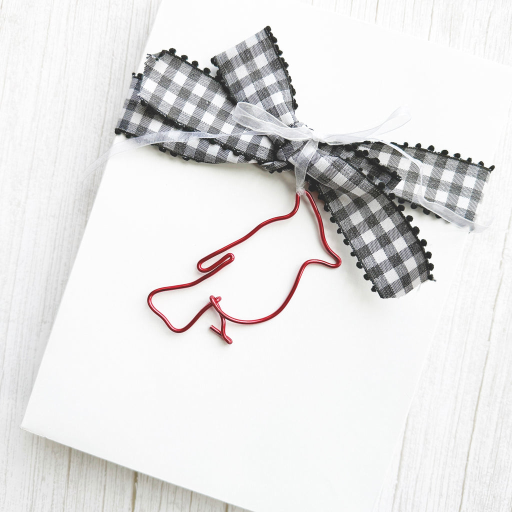 Red wire art cardinal gift tag with a sheer ribbon attached to a checkered bow on a package.