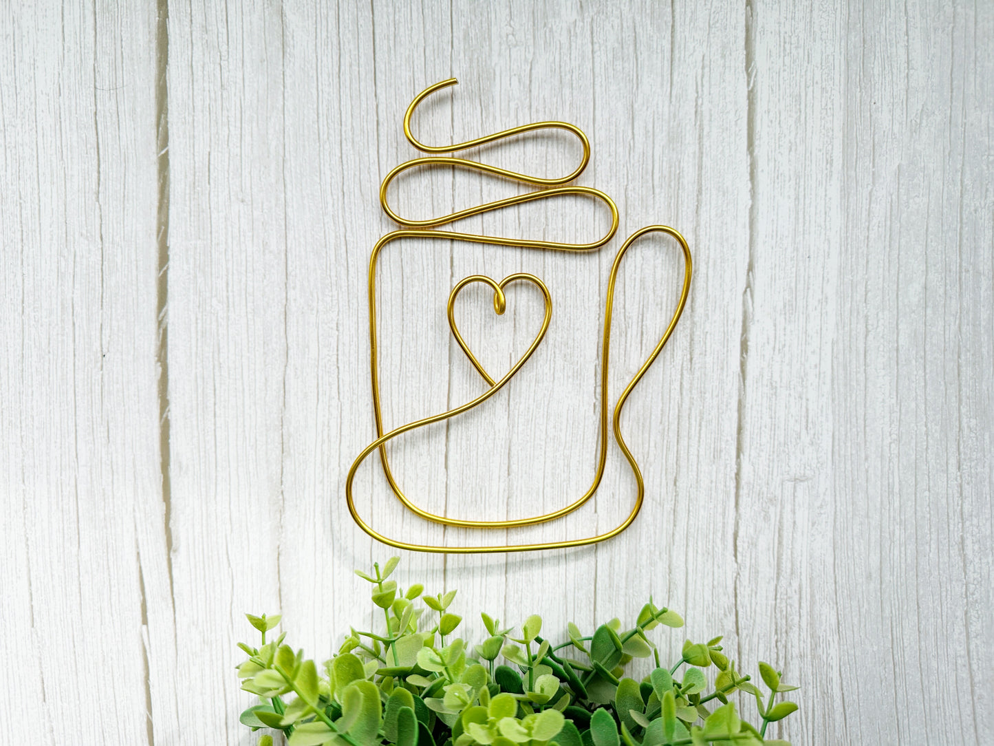 Decorative wall art of a mug with a heart on a light wooden background