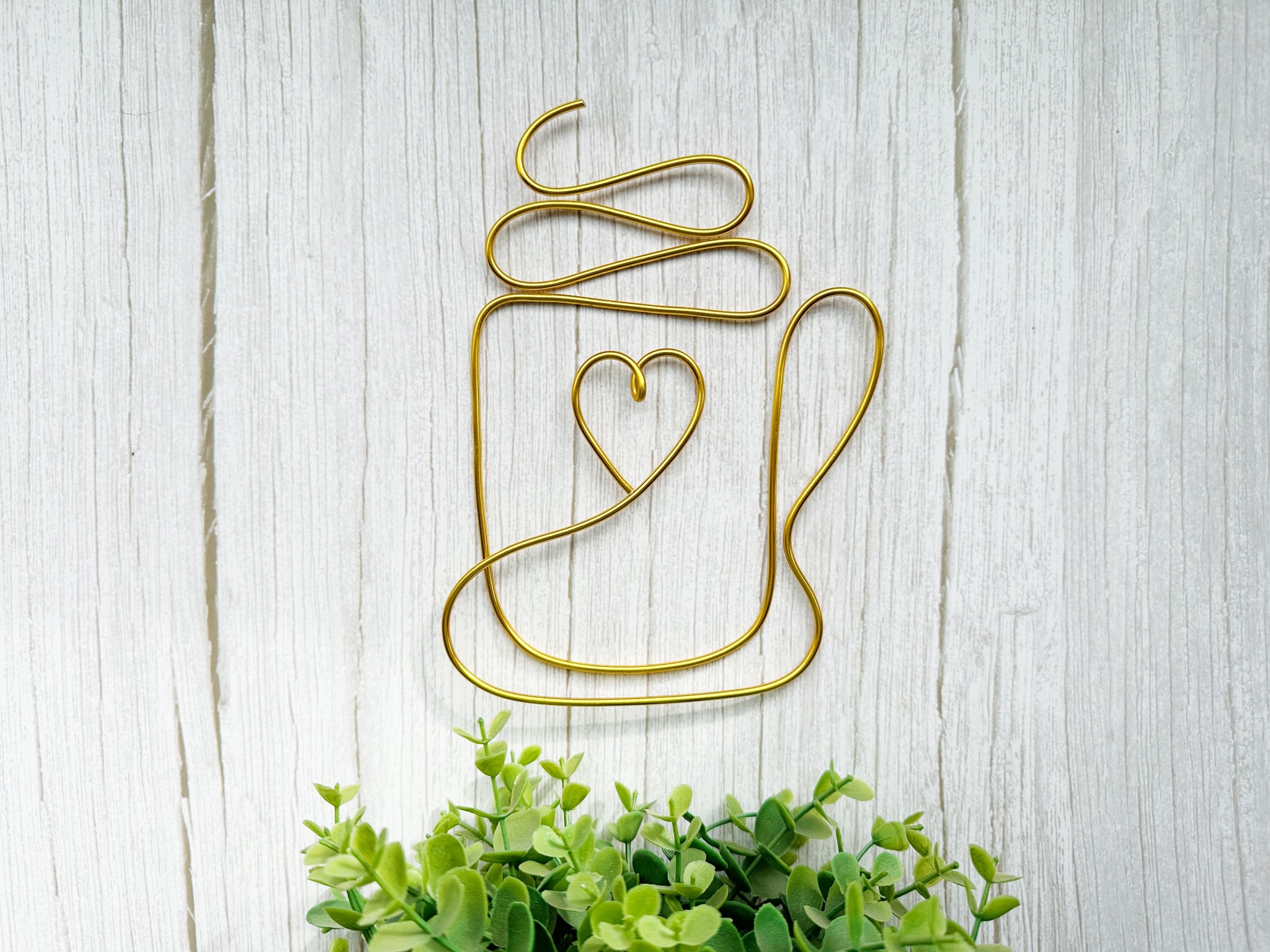 Decorative wall art of a mug with a heart on a light wooden background