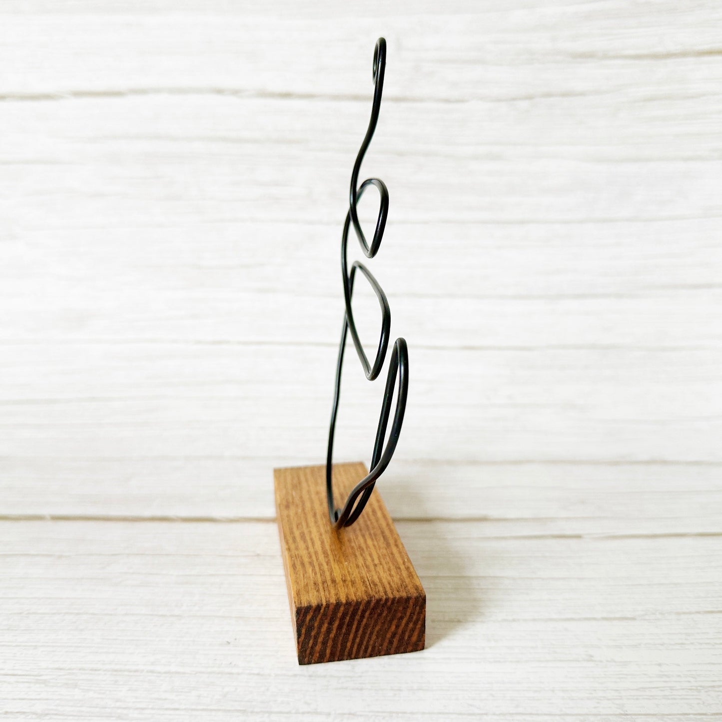 Decorative wire coffee mug sculpture on a wooden block against a white background