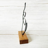Decorative wire coffee mug sculpture on a wooden block against a white background