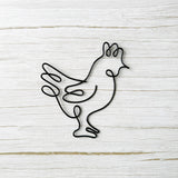 Black wire sculpture of a rooster on a light wooden background