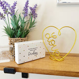 Decorative setup with lavender plant, 'Friday' sign, and a wire heart-shaped 'LOVE' sculpture on a wooden shelf.