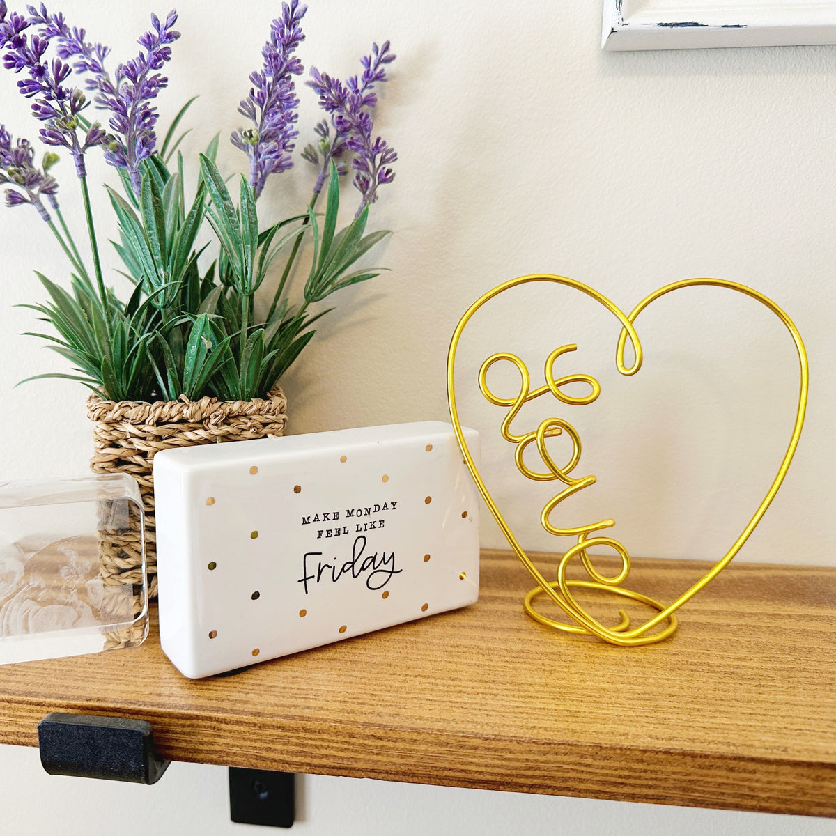 Decorative setup with lavender plant, 'Friday' sign, and a wire heart-shaped 'LOVE' sculpture on a wooden shelf.