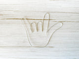 I love you hand shape made with silver colored wire laying on a light wood background.
