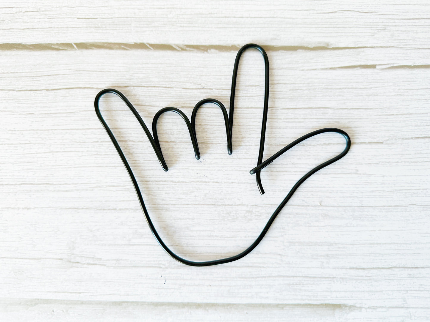 Black wire hand shape on a white wooden background