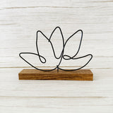 Gold wire lotus flower sculpture on a dark wood base, styled for minimalist or wellness-focused home decor.