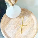 Wooden table with a white vase and gold wire number 1 laying down on the table.