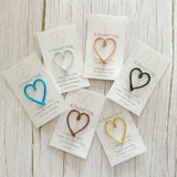 Heart-shaped clips on cards with text on a wooden surface
