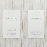 Two 'A Pocket Hug' cards on a wooden surface