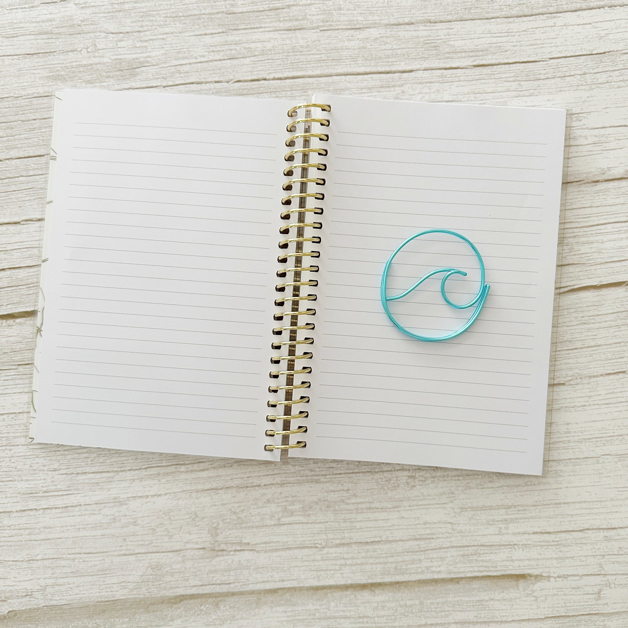 Open notebook with a blue wave bookmark on a wooden surface