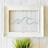 Framed artwork with a blue wave design on a wooden surface