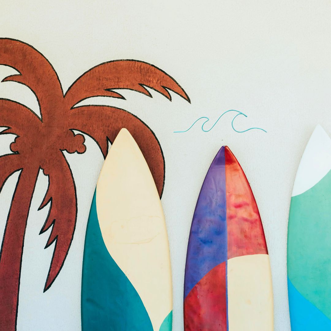 Colorful surfboards leaning against a wall with a palm tree and turquoise wire wave design.