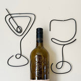 Wine bottle with black wire art of a martini glass and wine glass on a white background