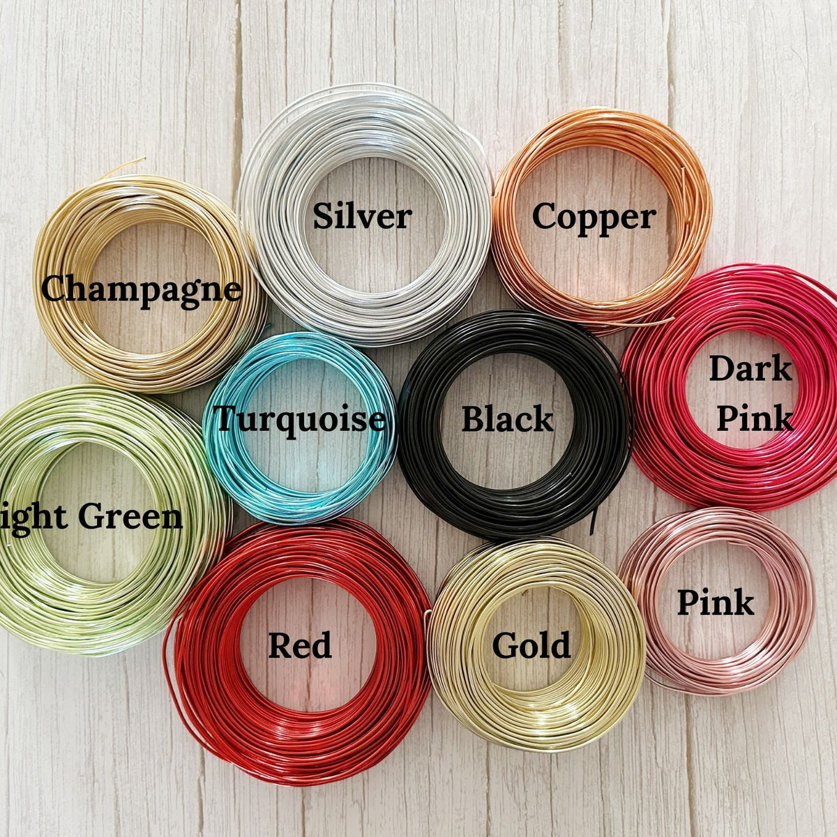 Color options for custom wire art including Black, Copper, Turquoise, Gold, Champagne, Red, Pink, Dark Pink and Silver—coiled wire samples displayed on a light textured background.